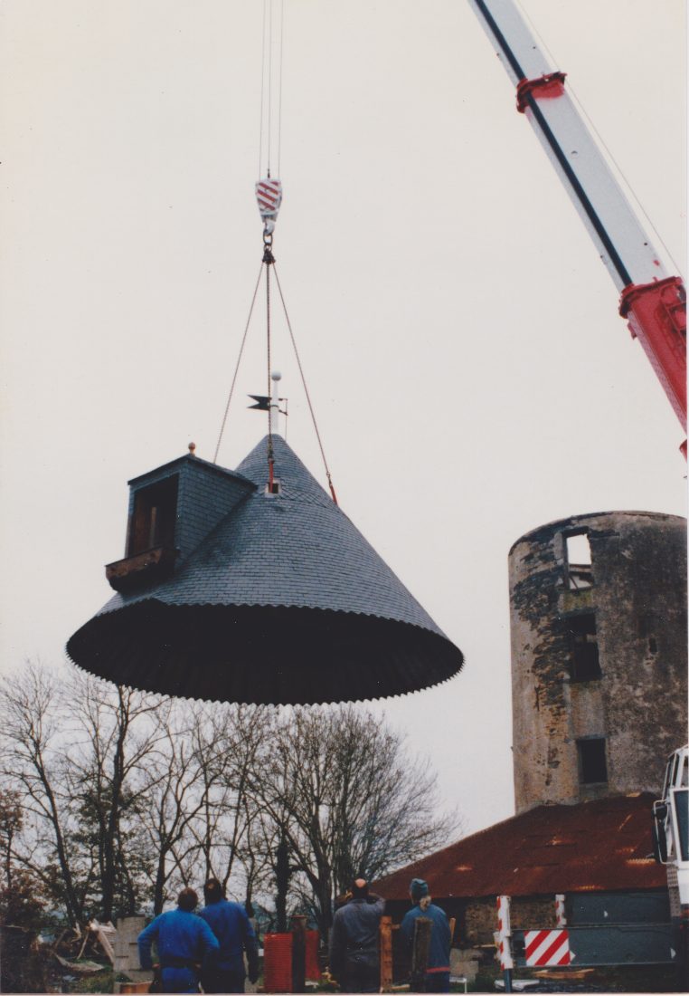 Une grue hisse la toiture neuve en ardoise jusqu'au sommet de la tour